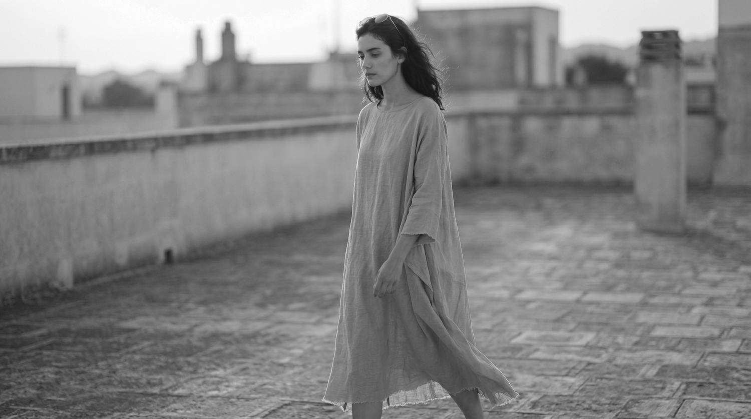 Woman in a long dress standing on a rooftop with a blurred background
