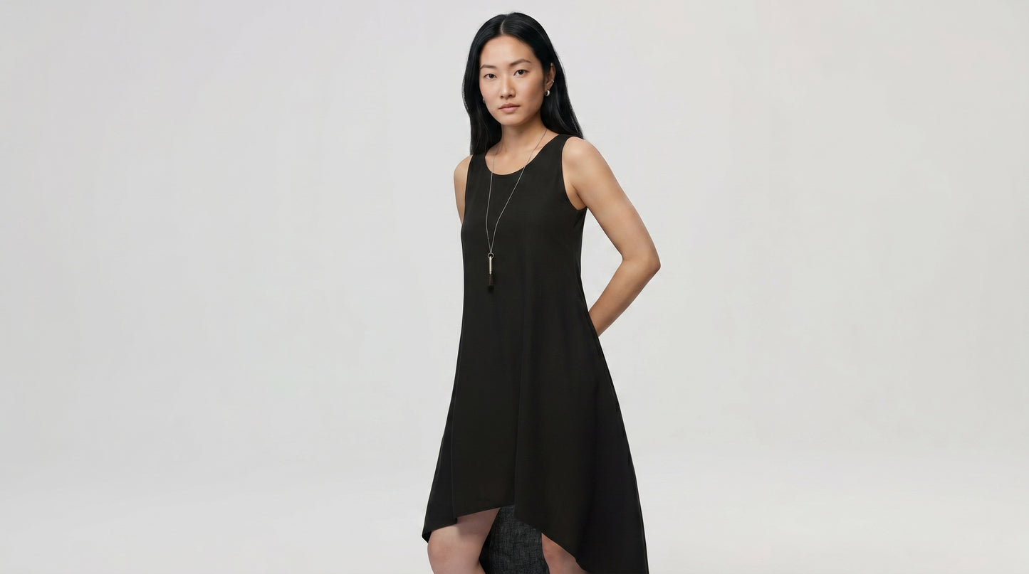 Woman wearing a black sleeveless dress against a plain background