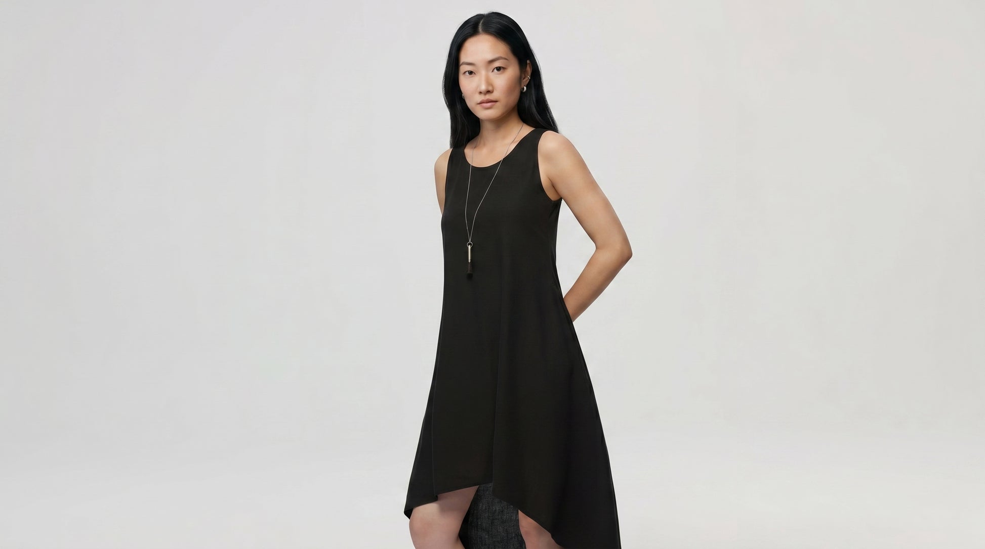 Woman wearing a black sleeveless dress against a plain background